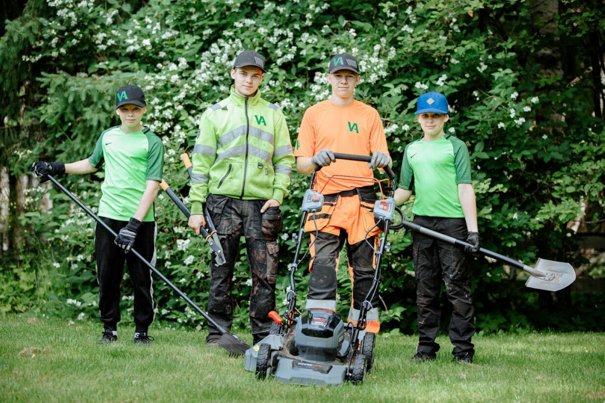 Kaksi vanhempaa ja kaksi nuorempaa veljestä pihatyövarusteet päällä puutarhassa.