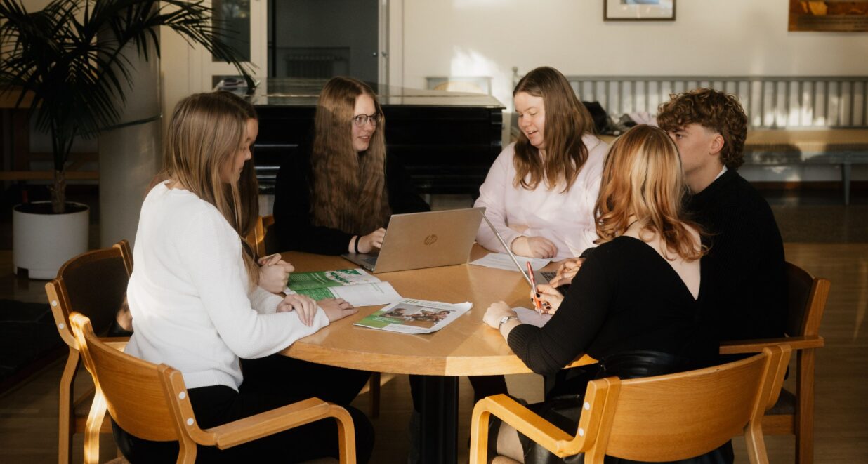 Nuoria kokoontuneena pöydän ääreen.