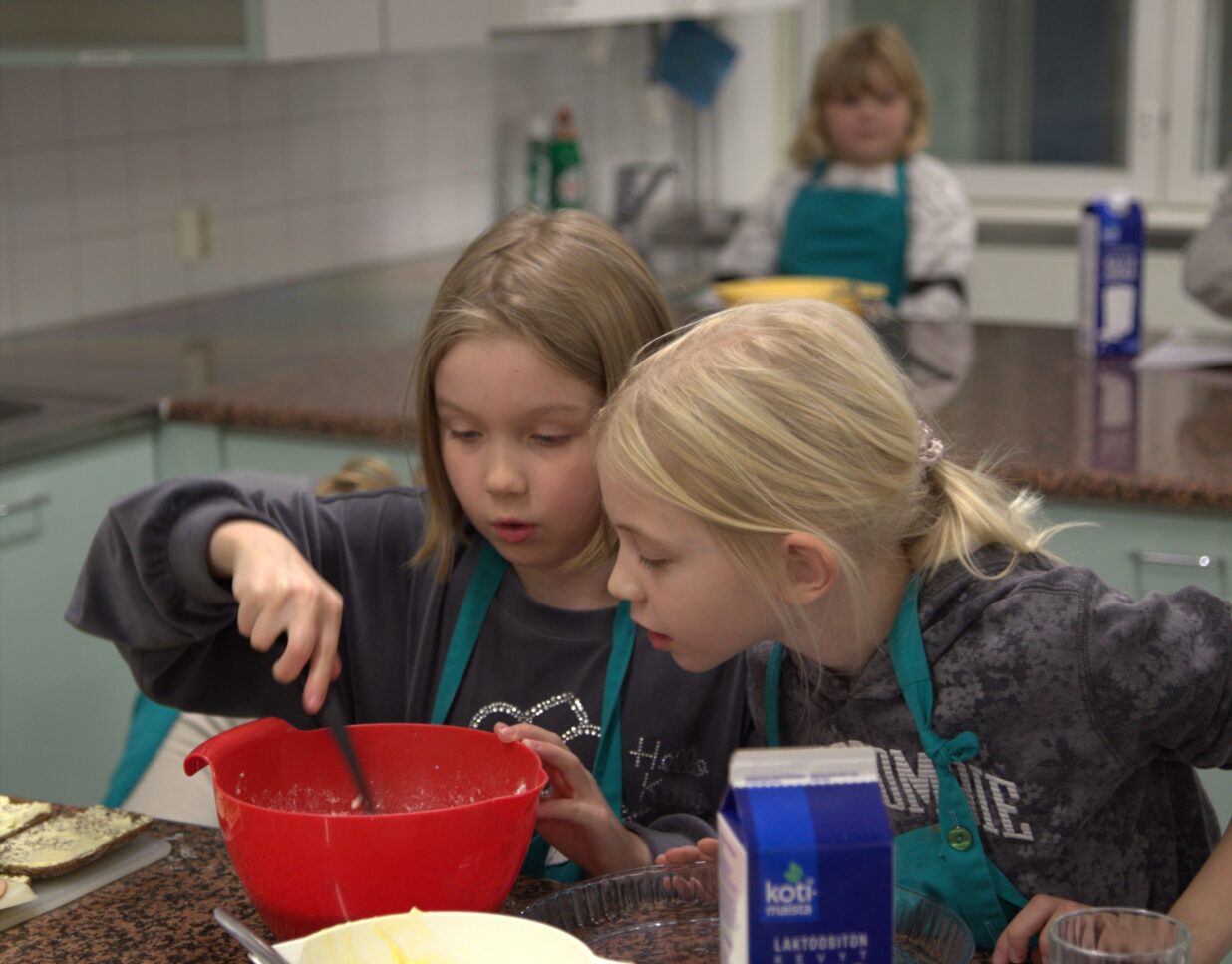 Kaksi kerholaista kurkistaa taikinakulhoon.