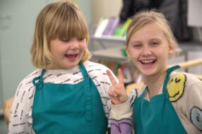 Kaksi iloista kerholaista essut päällä.