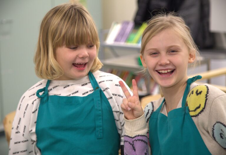 Kaksi iloista kerholaista essut päällä.