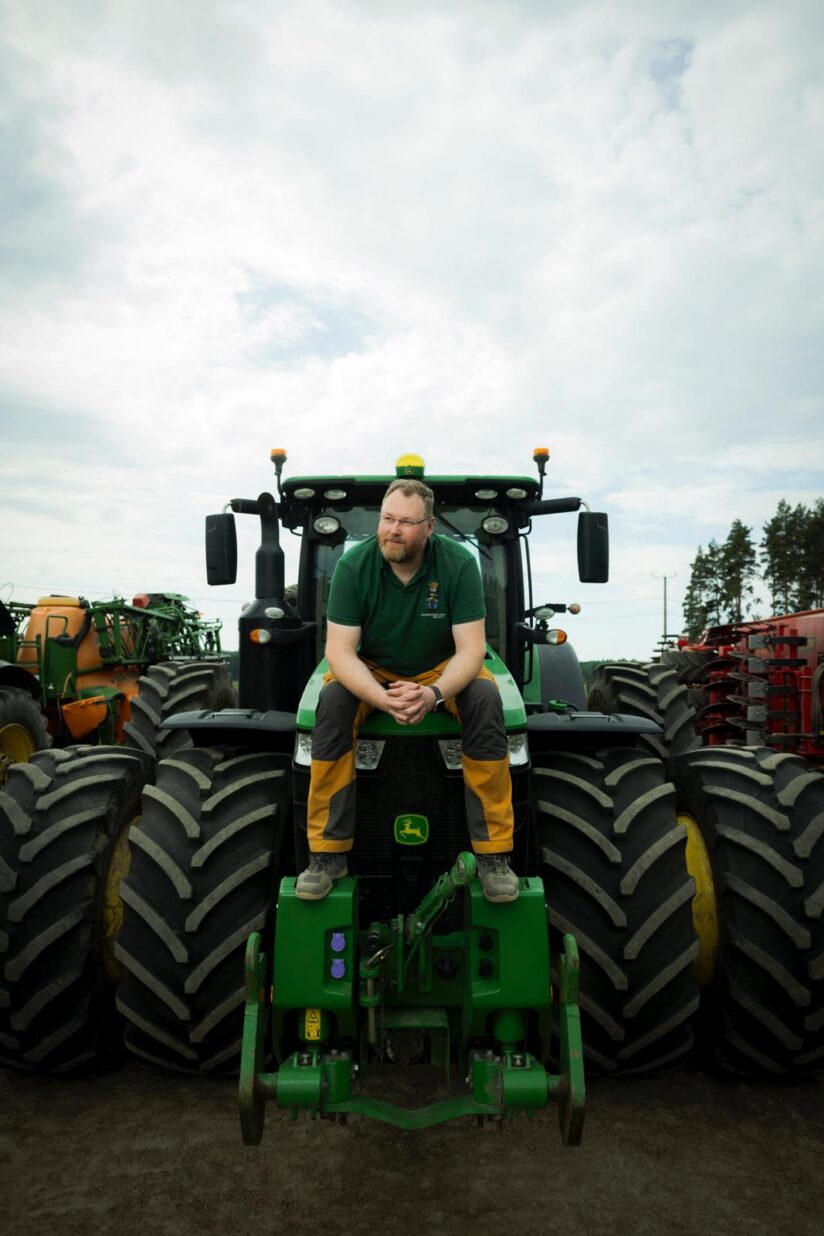 Kalle Vuori istuu maatalouskoneen renkaiden päällä.