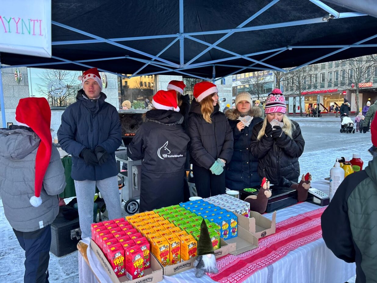 Nuoria päivystämässä torilla myyntikojulla. Myynnissä on pillimehuja ja makkaraa.